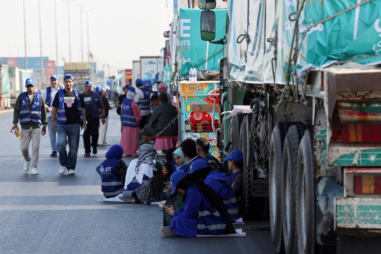 Egyptian volunteers rest and sit next to trucks loaded with humanitarian aid from Egypt's National Alliance For Civil Development Work (NACDW) as they are on their way to the Rafah border crossing to enter Gaza, after a ceasefire between Israel and Hamas in Gaza went into effect, on the Cairo-Ismailia desert road, in Egypt, October 16, 2025. REUTERS/Amr Abdallah Dalsh TPX IMAGES OF THE DAY