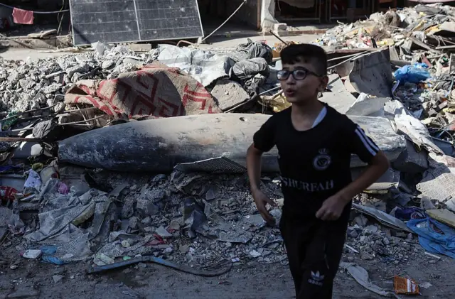 طفل فلسطيني يمشي أمام صاروخ إسرائيلي في أحد شوارع مدينة غزة، فلسطين، في 30 أكتوبر/تشرين الأول 2025. 