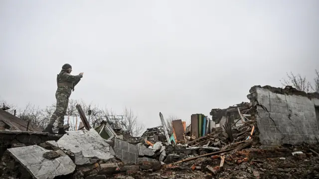 جندية تلتقط صورة لمنزل دمره قصف روسي في قرية فوزدفيزهيفكا الواقعة على خط المواجهة في مقاطعة بولوهي، منطقة زابوريزهيا، أوكرانيا، في 19 نوفمبر/تشرين الثاني 2025.