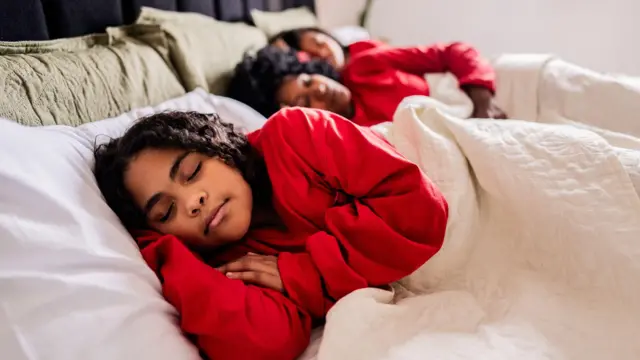 ثلاثة أطفال نائمون في سريرهم