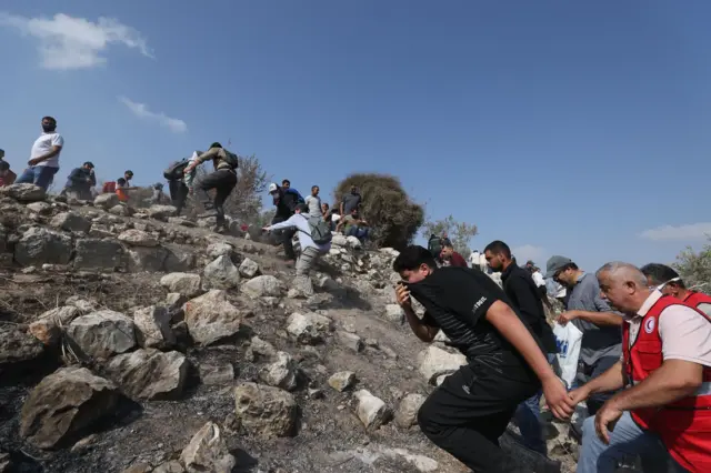 فلسطينيون وأعضاء من الهلال الأحمر يبتعدون بحثًا عن ملجأ من الغاز المسيل للدموع خلال اشتباكات بين القوات الإسرائيلية والمزارعين الفلسطينيين والنشطاء الدوليين بعد محاولتهم الوصول إلى مزارع الزيتون خارج قرية بيت ليد وبالقرب من بؤرة استيطانية إسرائيلية، بالقرب من مدينة قلقيلية بالضفة الغربية، 7 نوفمبر/تشرين الثاني 2025. ووفقًا لوزارة الصحة الفلسطينية، أصيب أكثر من اثني عشر فلسطينيًا خلال اشتباكات مع القوات الإسرائيلية.