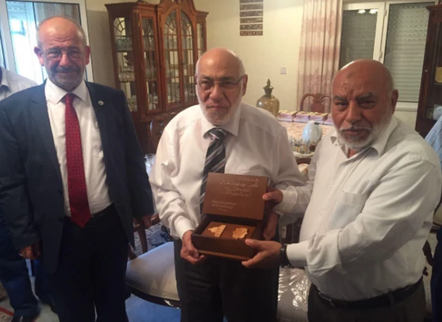 الدكتور زغلول النجار يتلقى تكريماً من نقابة المهندسين الأردنية عام 2017 ويظهر في الصورة واقفاً ويتوسط رجلين، بينما يرتدي قميصاً أبيض وسروالاً رمادي اللون ووربطة عنق.