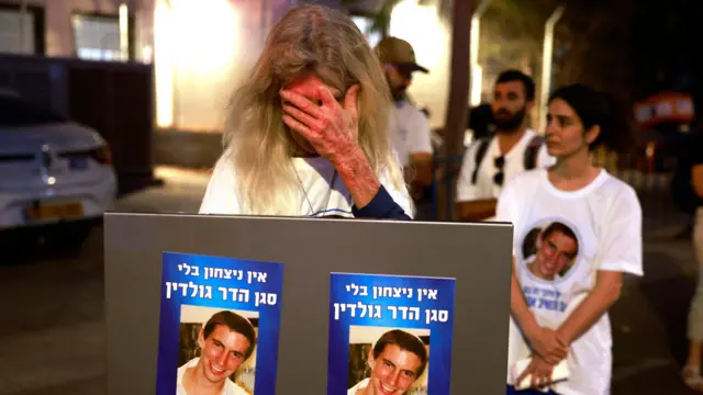 امرأة إسرائيلية تحمل صوراً للملازم هدار غولدين، تتفاعل وهي تنتظر وصول الجثة التي يُعتقد أنها لغولدين، الذي تزعم حماس أنها أعادته كجزء من اتفاق وقف إطلاق النار بين إسرائيل والفصائل الفلسطينية في غزة، خارج المركز الوطني للطب الشرعي في تل أبيب، في 9 نوفمبر/تشرين الثاني 2025.