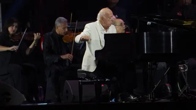 الموسيقار المصري عمر خيرت يعزف على البيانو ويقود فرقته ببذلة بيضاء