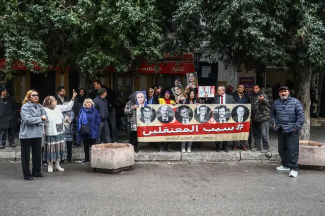 متظاهرون يحملون صور معارضين سياسيين خلال احتجاج نُظم أمام محكمة في تونس العاصمة، في 27 نوفمبر/تشرين الثاني 2025