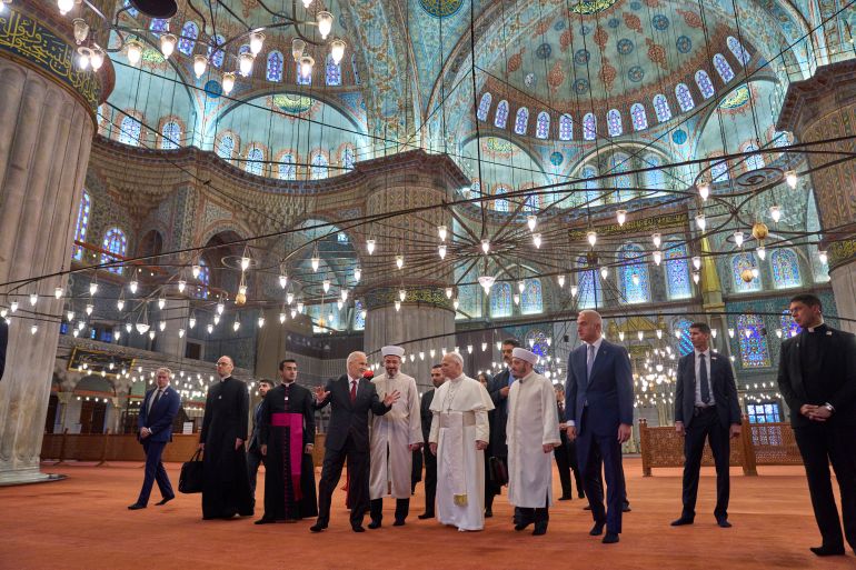 Pope Leo XIV, center, walks with Muezzin Musa Asgın Tunca, fourth from left, Istanbul's Mufti Emrullah Tuncel, fifth from left, the Imam of Mosque Sultanahmet Fatih Kaya, seventh from left, and Turkish Minister for Culture and Tourism Mehmet Nuri Ersoy, eighth from left, during a visit of the Sultan Ahmed Mosque in Istanbul, Saturday, Nov. 29, 2025. (AP Photo/Domenico Stinellis)