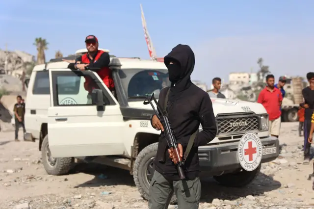 مسلح فلسطيني من حماس يقف قرب سيارة تابعة للجنة الدولية للصليب الأحمر، بينما تجري عملية البحث عن جثث رهائن إسرائيليين قتلى في مدينة غزة في 2 نوفمبر/ تشرين الثاني 2025