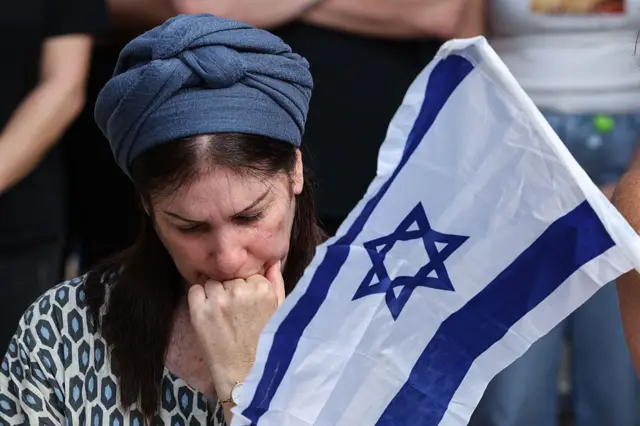 سيدة إسرائيلية تبكي بجانب علم إسرائيل خلال جنازة عوز دانيال، العريف الإسرائيلي البالغ من العمر 19 عامًا، الذي قُتل في هجمات 7 أكتوبر/تشرين الأول 2023 على جنوب إسرائيل، ونُقل جثمانه إلى غزة، في مقبرة عسكرية في كفار سابا في 6 نوفمبر/تشرين الثاني 2025.