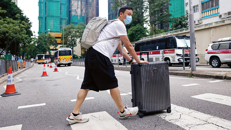 أحد سكان المبنى يدفع حقيبته عبر الطريق بعد أن جمع متعلقاته. رويترز