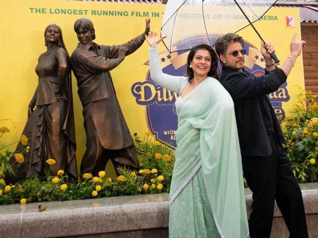 يظهر شاروخان وكاجول ديفغان وهما يلتقطان الصور خلال إزاحة الستار عن تمثال برونزي جديد يجسّدهما، وذلك في فعالية إطلاق تمثال رجوع العاشث المجنون ضمن مسار مشاهد في الساحة في ليستر سكوير، في 4 ديسمبر/كانون الأول 2025 في لندن، إنجلترا.