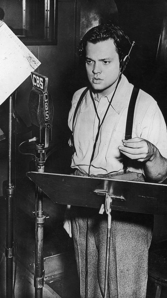 أورسون ويلز يقف أمام الميكروفون في استوديو إذاعة سي بي إس 