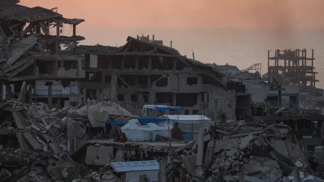 فلسطينيون يسيرون بين المباني المدمرة شمال مدينة غزة