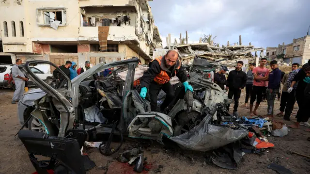 فلسطينيون يتفقدون موقع الغارة الإسرائيلية على سيارة في مدينة غزة، 13 ديسمبر 2025