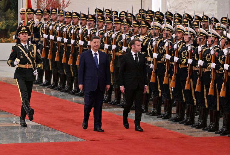 France's President Emmanuel Macron, right, and China's President Xi Jinping, center, review honour guards during a state visit at the Great Hall of the People in Beijing Thursday, Dec. 4, 2025. (Adek Berry/Pool Photo via AP)