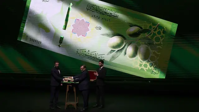 الرئيس السوري أحمد الشرع وحاكم مصرف سوريا المركزي عبد القادر حصرية حفل إطلاق العملة الجديدة في قصر المؤتمرات دمشق الاثنين 29-12-2025