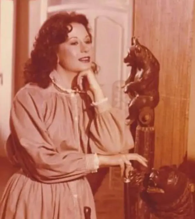 الفنانة الراحلة سمية الألفي أثناء أدائها لدور الأميرة نورهان في المسلسل المصري "ليالي الحلمية"، وتقف الألفي أمام تمثال، بينما ترتدي فستاناً طويلاً ذا أكمام طويلة وينساب شعرها الكثيف أسفل ظهرها، وتضع أحمر شفاة.