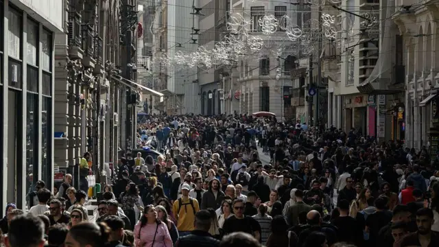 أشخاص يسيرون في أحد شوارع إسطنبول المكتظ، وتزين الشارع زينة عيد الميلاد.

