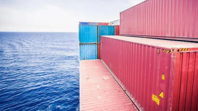 صورة تظهر حاويات لنقل البضائع مركونة على رصيف بحري.