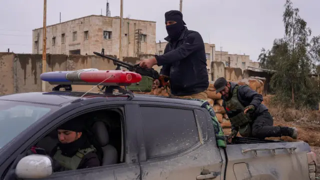 يقف أحد أفراد قوات الأمن السورية في مؤخرة سيارة خارج سجن الأقطان، حيث يُحتجز بعض سجناء تنظيم الدولة الإسلامية، في الرقة، سوريا، 23 يناير/كانون الثاني 2026.