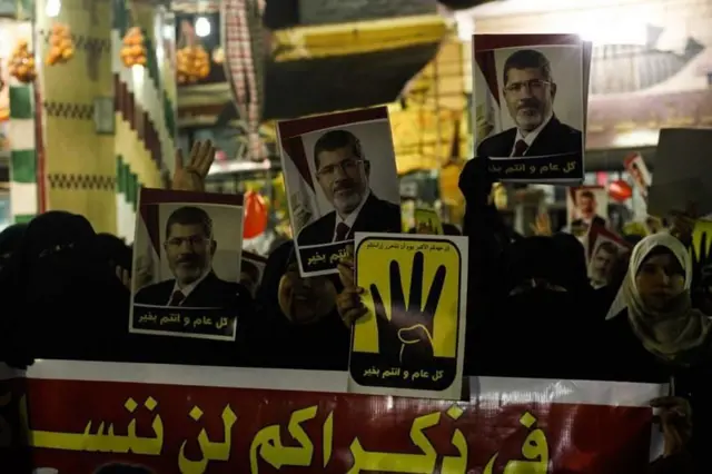 رُفعت لافتات تحمل صور محمد مرسي وشعار رابعة في مظاهرة في غزة عام 2016.