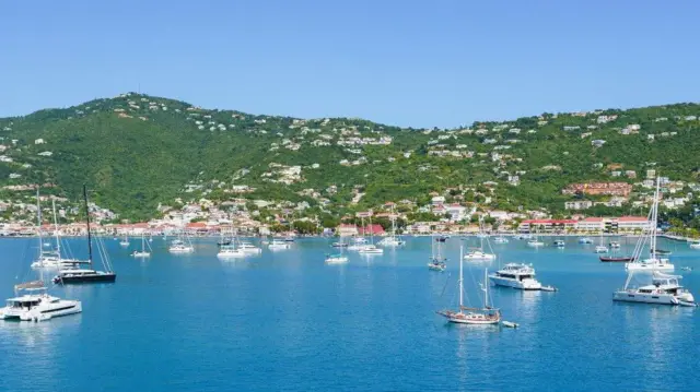 مراكب بيضاء على صفحة مياه زرقاء، في حضن تلال خضراء مرصّعة بمبان بيضاء اللون، في جزيرة سانت توماس