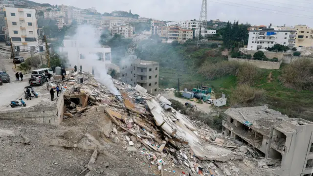 يتفقد الناس مبنىً مدمراً إثر غارة جوية إسرائيلية على قرية قناريت، جنوب لبنان، في 22 يناير/كانون الثاني 2026. 