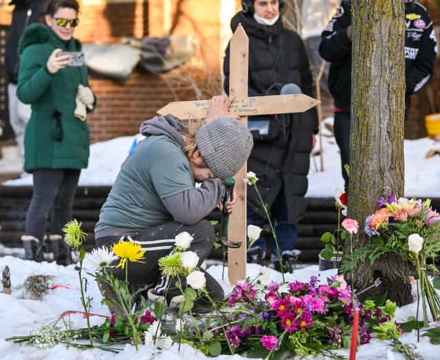 امرأة تضع صليباً على نصب تذكاري مؤقت في مكان الحادث الذي قُتلت فيه امرأة برصاص أحد عملاء إدارة الهجرة والجمارك (ICE) في مينيابوليس، مينيسوتا، الولايات المتحدة الأمريكية، في 7 يناير 2026.