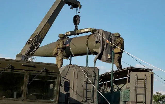 جنود روس يقومون بتحميل صاروخ نووي غير استراتيجي لمنظومة صواريخ إسكندر العملياتية التكتيكية، في موقع غير مُعلن عنه في روسيا، بتاريخ 21 مايو/ آيار 2024