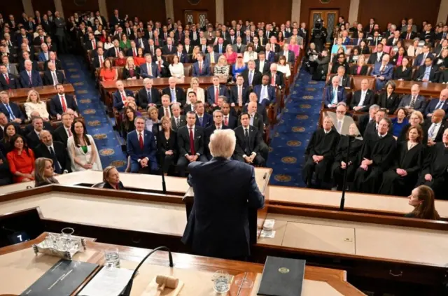  دونالد ترامب من الخلف يبدو أنه يرتدي بدلة رسمية سوداء، أثناء إلقائه لخطاب أمام جلسة مشتركة للكونغرس في مبنى الكابيتول في واشنطن العاصمة.