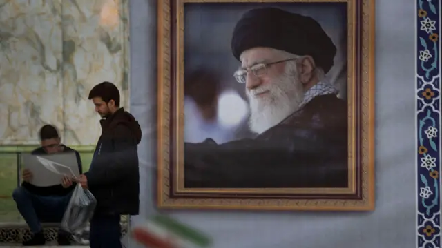يقف رجل إيراني بجوار صورة المرشد الأعلى الإيراني، آية الله علي خامنئي، بعد مشاركته في مراسم إحياء الذكرى السابعة والأربعين لانتصار الثورة الإسلامية الإيرانية في ضريح آية الله الخميني في مقبرة بهشت ​​زهراء جنوب طهران، إيران، في 1 فبراير/شباط 2026 