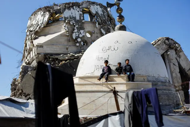 أطفال فلسطينيون يجلسون فوق أنقاض أحد المساجد التي دُمّرت خلال حرب غزة، في مدينة غزة، 11 فبراير/شباط 2026.