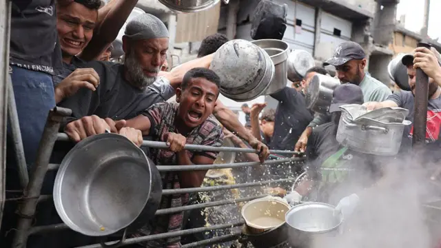 صورة من أعلى - فلسطينيون يكافحون للحصول على حصصهم الغذائية خارج مركز توزيع مكتظ في بيت لاهيا شمال قطاع غزة، في 15 مايو/أيار 2025. 