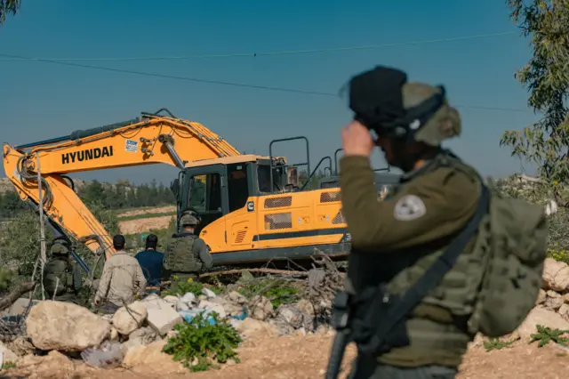 جنود إسرائيليون في حالة تأهب بينما تعمل آلة إسرائيلية في أرض في قرية بيت عوا قرب الخليل في الضفة الغربية المحتلة في 5 فبراير/ شباط 2026.