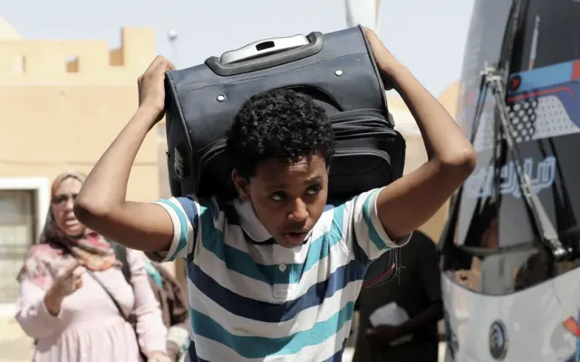 صورة لشاب سوداني يحمل حقيبة سفره خلال عبوره من السودان إلى مصر