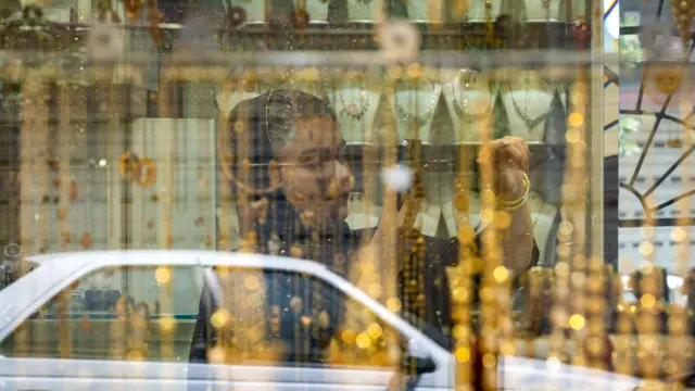 شابة إيرانية تلتقط صورًا وهي تقف أمام متجر ذهب في سوق بمدينة بوشهر الإيرانية، في 28 أبريل/نيسان 2024. 