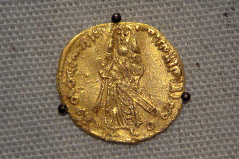 دينار أمويّ يَعود إلى سنة 695م، في عهد الخليفة عبد الملك بن مروان، وهو أوّل من أمر بسك الدنانير باللغة العربية، ويَظهر رسم له على العملة، كما أن الشهادة مكتوبة حول اسمه أيضاً بالخط الكوفي