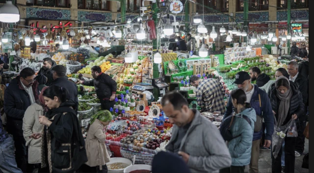 إيرانيون رجالاً ونساء يرتدون ملابس شتوية يتسوقون في أحد المحلات في سوق تجريش الشعبي بالعاصمة طهران
