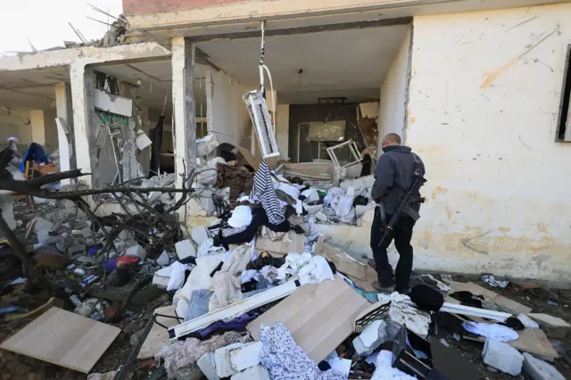 يسير أزران ديفيد بجوار منزله المتضرر في ديمونا، جنوب إسرائيل، في 22 مارس/آذار 2026، عقب ليلة من الهجمات الصاروخية الإيرانية التي أسفرت عن إصابة عشرات الإسرائيليين