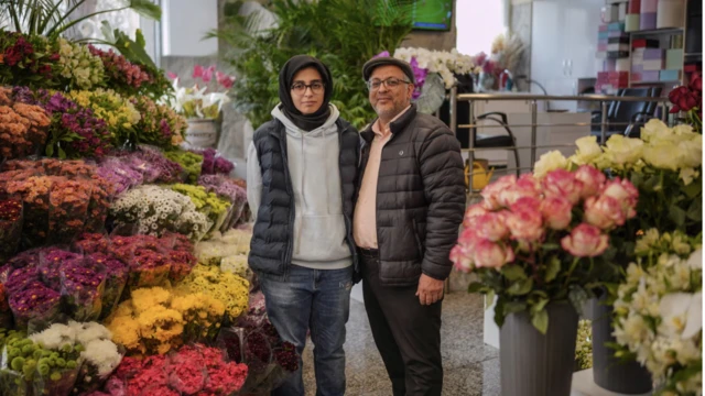 حسن وانبته ساجدة يقفان في محل بيع الزهور الخاص وحولهما نباتات بألوان زاهية في العاصمة طهران