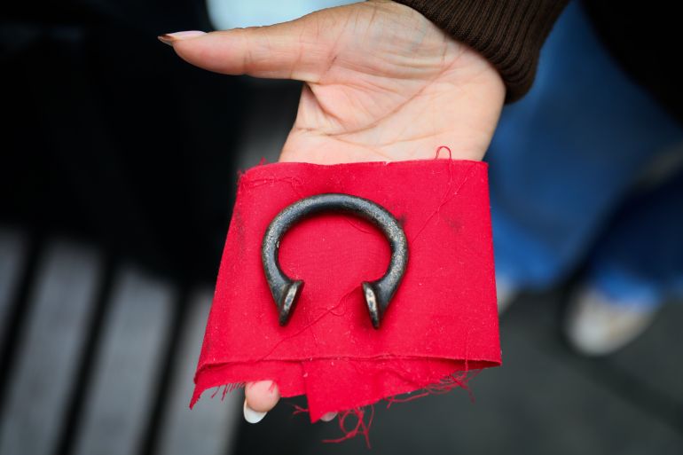 LONDON, ENGLAND - OCTOBER 12: A participant of the tour holds a manilla, a metal which gradually became the principal currency of the slave trade. on October 12, 2024 in London, England. Founded in 2020 by Black historian and researcher, Darrel Blake, the City Of London: Slave Trade Money Trail Tour uncovers the untold history of Britain's early involvement in the transatlantic slave trade. The tour explores the historical ties between London's financial institutions and the plantation economy, exposing how wealth from the slave trade helped shape the city. Driven by a desire to challenge the conventional narratives of British history, Darrel runs the walking tour from March to December, with special events during Black History Month in October.(Photo by Alishia Abodunde/Getty Images)