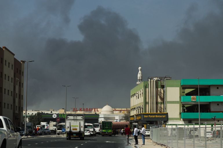 People look at thick smoke rising from the site of a reported Iranian strike in Dubai on March 1, 2026.
