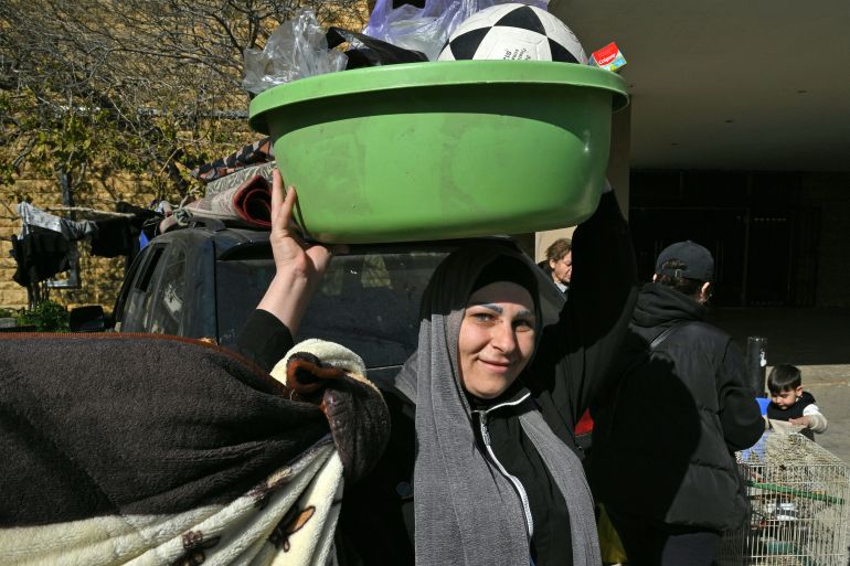 A woman carries her belongings at a school transformed into a shelter for displaced people in the town of Dekwaneh north of Beirut on March 5, 2026.