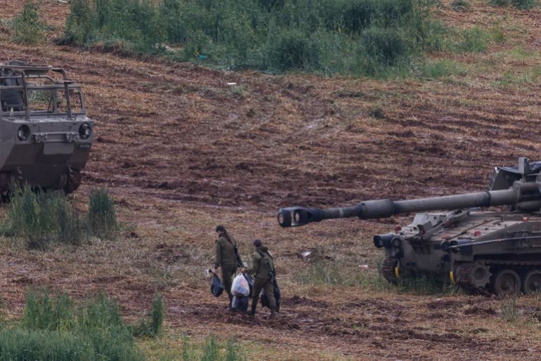 Israeli army soldiers walk next to a self-propelled Howitzer artillery gun positioned in the upper Galilee in northern Israel near the border with southern Lebanon on March 29, 2026.