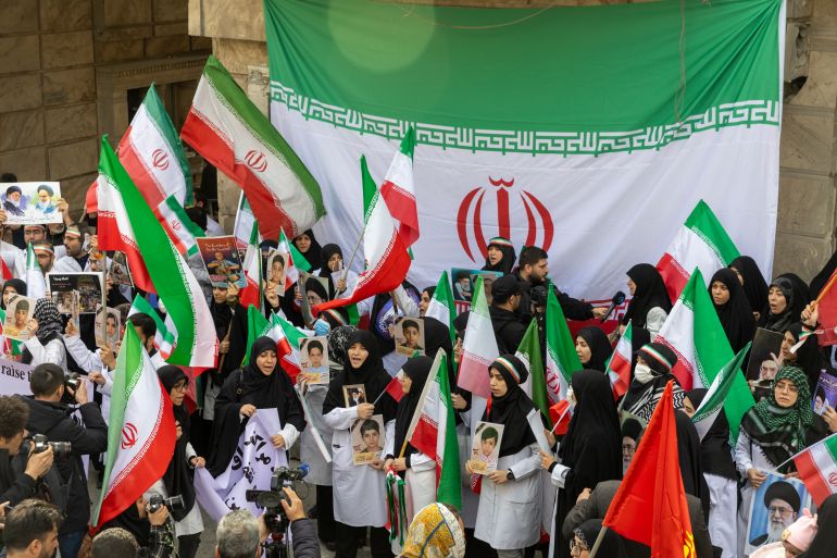 TEHRAN, IRAN - MARCH 7: People hold flags and banners at a protest by medical professionals outside Gandhi Hospital, which was damaged in an airstrike earlier in this week, on March 7, 2026 in Tehran, Iran. The United States and Israel continued their joint attack on Iran that began on February 28. Iran retaliated by firing waves of missiles and drones at Israel, and targeting U.S. allies in the region. (Photo by Majid Saeedi/Getty Images)