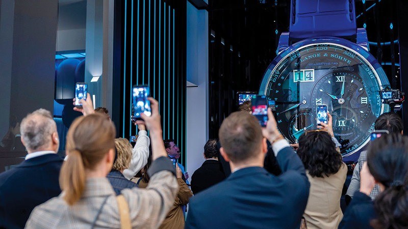 زوار يلتقطون صوراً بهواتفهم لساعة فاخرة في أحد أجنحة &laquo;المعرض&raquo;. أ.ب