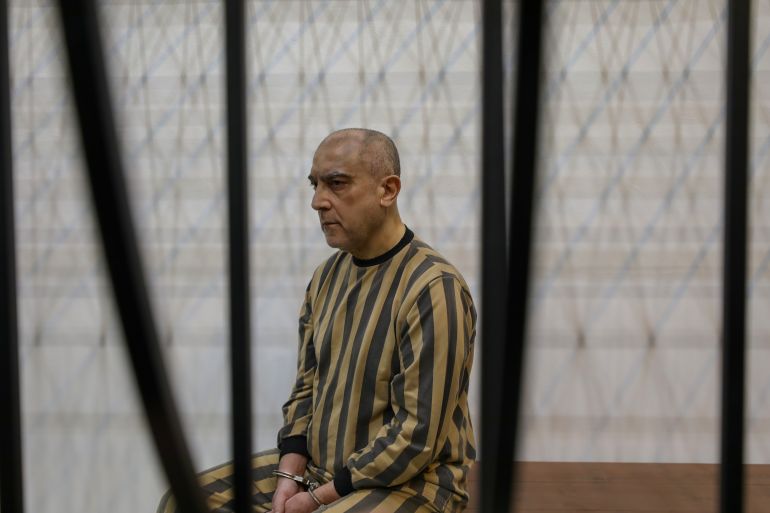 عاطف نجيب، ابن عمّ الرئيس السوري المخلوع بشار الأسد، يقف خلف القضبان في قفص مخصص داخل قاعة المحكمة خلال محاكمته في محكمة الجنايات الرابعة بقصر العدل في دمشق، سوريا، 26 أبريل/نيسان 2026