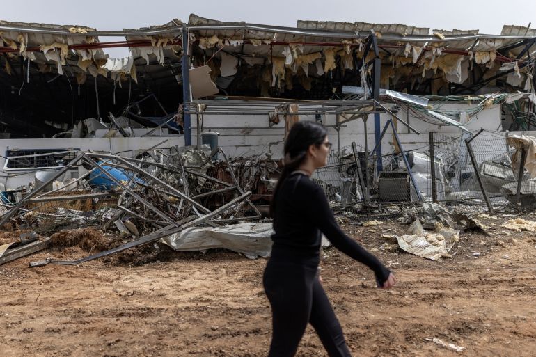A woman walks past a factory that got hit by a missile in Petah Tikva, east of Tel Aviv, on April 3, 2026.