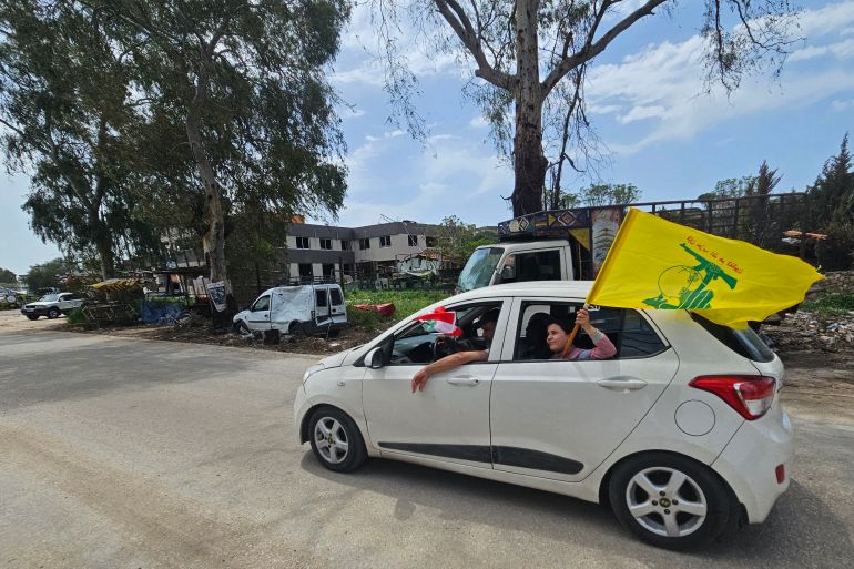 A displaced resident carries a flag of Hezbollah while driving back to his home in the southern Lebanese city of Nabatieh on April 17, 2026.