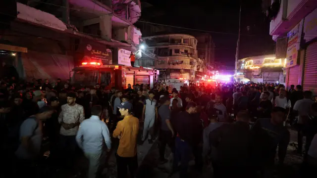 فلسطينيون يتجمعون في الشارع لتفقد موقع غارة جوية إسرائيلية استهدفت مبنى سكنياً في مدينة غزة.