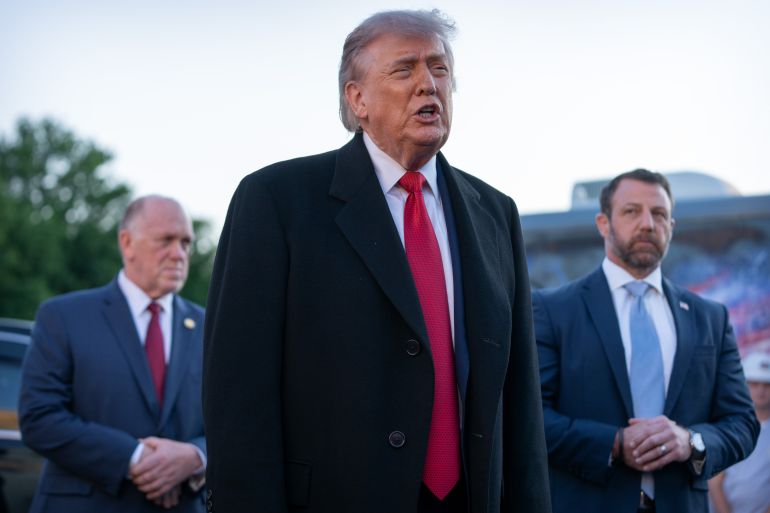 President Donald Trump, center, flanked by White House border czar Tom Homan, left, and Homeland Security Secretary Markwayne Mullin, right, talks as he visits the Lincoln Memorial Reflecting Pool to see the new blue protective coating being applied as part of a renovation project, Thursday, May 7, 2026, in Washington. (AP Photo/Mark Schiefelbein)